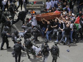 FILE - Israeli police confront with mourners as they carry the casket of slain Al Jazeera veteran journalist Shireen Abu Akleh during her funeral in east Jerusalem, Friday, May 13, 2022. An Israeli police investigation reveals that police engaged in misconduct during the funeral of Abu Akleh. Those who supervised the event will not face serious punishment, according to an Israeli daily newspaper report published on Thursday, June 16, 2022.
