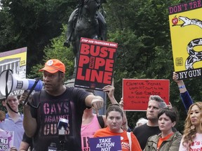 Jay Walker, third from left, co-founder of Gays Against Guns, speaks into a megaphone during a rally against the Supreme Court decision striking down New York's gun law, Thursday, June 23, 2022, in New York. When the U.S. Supreme Court struck down New York's tight restrictions on who can carry a handgun, condemnation erupted from liberal leaders and activists.