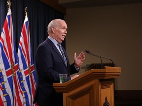 Premier John Horgan answers questions during a news conference in the press theatre at the legislature in Victoria, Friday, March 11, 2022.