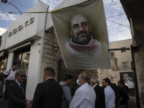 FILE - Family members receive condolences under a poster with a picture of Palestinian Authority outspoken critic Nizar Banat, during his memorial service, in the West Bank city of Ramallah, Saturday, Oct. 16, 2021. Amnesty International said Friday, June 24, 2022, that the Palestinian Authority has failed to hold its security forces accountable for the death of Banat, an activist in police custody a year ago.