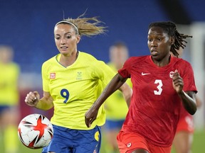 Sweden's Kosovare Asllani, left, and Canada's Kadeisha Buchanan battle for the ball during the women's final soccer match at the 2020 Summer Olympics, Friday, Aug. 6, 2021, in Yokohama, Buchanan has signed a three-year deal with English soccer giant Chelsea. Buchanan joins the storied London club's women's team after a highly successful run with Lyon.