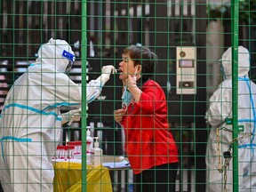 A health worker takes a COVID swab sample from a woman in Shanghai in June, 2022. Hector Retamal/AFP/Getty Images
