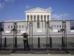 An officer rests on a fence outside the Supreme Court in Washington, Friday, June 24, 2022. The Supreme Court has ended constitutional protections for abortion that had been in place nearly 50 years, a decision by its conservative majority to overturn the court's landmark abortion cases.