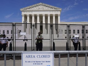 U.S. Capitol Police officers stand post behind the temporary anti-scaling fence surrounding the U.S. Supreme Court, on Tuesday, June 28, 2022, in Washington. The Supreme Court has put on hold a lower court ruling that Louisiana must draw new congressional districts before the 2022 elections to increase Black voting power.