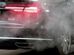 A luxury Audi car is surrounded by exhaust gases as it is parked with a running engine in front of the Chancellery in Berlin, Germany, Wednesday, Nov. 20, 2019. Germany's transport minister said Thursday that he opposes plans to ban the sale of new cars with combustion engines across the European Union in 2035, arguing this would discriminate against vehicles powered with synthetic fuels. EU lawmakers voted Wednesday to back the measure that requires automakers to cut carbon-dioxide emissions by 100% by the middle of the next decade, effectively prohibiting the sale in the 27-nation bloc of new cars powered by gasoline or diesel.