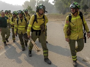 Firefigters walk in the area of a wildfire in Pujerra, Malaga, on Thursday, June 9, 2022. Emergency services deployed almost 1,000 firefighters, military personnel and support crews Thursday to fight a wildfire that has forced the evacuation of some 2,000 people in southern Spain amid fears that torrid weather may feed the blaze.
