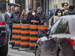 People line up outside a grocery store in Toronto on Sunday, May 17, 2020. A new survey has found that Canadians are feeling stressed from soaring inflation, particularly higher grocery prices.