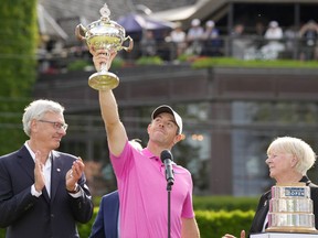 Golf Canada president Liz Hoffman, right, and RBC president David I. McKay look on as Rory McIlroy of Northern Ireland raises the trophy after winning the final round of the Canadian Open in Toronto on Sunday, June 12, 2022.