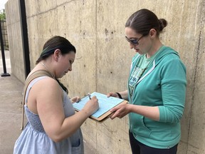 Raevahnna Richardson signs an initiative petition supporting a gun-safety ballot measure on Tuesday, June 7, 2022, outside a library in Salem, Ore., as signature gatherer Rebecca Nobiletti holds the clipboard. Richardson said she signed " to keep our kids safe, because something needs to change." The killings in Uvalde, Texas, has given the Oregon ballot initiative huge momentum, with the number of volunteers doubling to 1,200 and signatures increasing exponentially, according to organizers. If enough registered voters sign the petitions, the initiative will be on the November ballot.