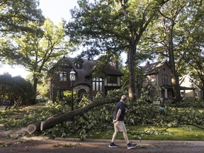 A person walks past a home in Riverside where residents begin cleanup from Monday evening's storm that raced across the Chicago area on Tuesday, June 14, 2022. A supercell thunderstorm with winds in excess of 80 mph (129 kph) toppled trees and damaged power lines Monday evening as it left a trail of damage across the Chicago area and into northwestern Indiana, the National Weather Service said.
