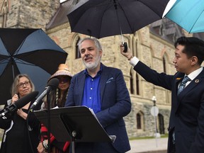 Green Party Interim Leader Amita Kuttner holds an umbrella for newly announced Deputy Leader Luc Joli-Coeur during a news conference on Parliament Hill in Ottawa, on Tuesday, June 21, 2022.