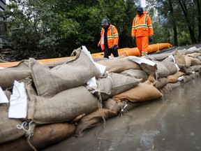 Workers sandbag around the River Cafe restaurant as heavy rainfall forecast for southern Alberta is prompting the city of Calgary to declare a local state of emergency, in Calgary, Alta., Tuesday, June 14, 2022.THE CANADIAN PRESS/Jeff McIntosh
