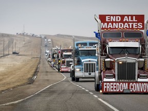 Demonstrators against a COVID-19 vaccine mandate leave in a truck convoy after blocking the highway at the busy U.S. border crossing near Coutts, Alta., on Tuesday, Feb. 15, 2022. Setting of trial dates for four men charged with conspiracy to commit murder at the protest in southern Alberta has been delayed another month after one of the accused fired his lawyer.