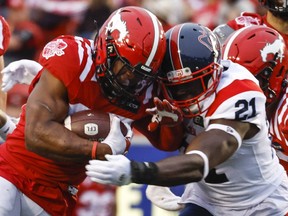 Montreal Alouettes linebacker Chris Ackie, right, tackles Calgary Stampeders running back Ka'Deem Carey during second half CFL football action in Calgary, Thursday, June 9, 2022.THE CANADIAN PRESS/Jeff McIntosh