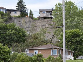 A house stands on the side of a landslide that destroyed a house and forced 77 residences to be evacuated, Tuesday, June 21, 2022, in Saguenay, Que.