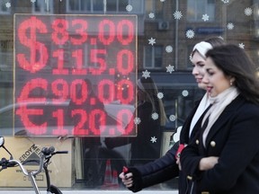 FILE - People walk past a currency exchange office screen displaying the exchange rates of U.S. Dollar and Euro to Russian Rubles in Moscow's downtown, Russia, Monday, Feb. 28, 2022. As the ruble strengthens to levels not seen in seven years, Russia's minister of economic development warned Wednesday, June 29, 2022 that the country's businesses could suffer if the trend persists.