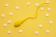 The yellow sperm model is on a yellow polka-dotted background made with white pills. Concept of diagnosis and treatment of male infertility and sperm problems