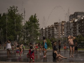 Children and adults cool off in a fountain in a park by the river in Madrid, Spain, Wednesday, June 15, 2022. Spain's weather service says a mass of hot air from north Africa is triggering the country's first major heatwave of the year with temperatures expected to rise to 43 degrees Celsius (109 degrees Fahrenheit) in certain areas.
