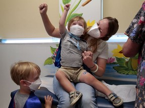 "Give it to the crowd!," yells Jen Maddock as she raises her fist in celebration with son Will, 23 months, after the youngster received his COVID-19 vaccination at Southwest Pediatrics on Wednesday, June 22, 2022, in St. Louis. Will and his brother Jack, 3, waiting his turn at left, wore superhero capes for the occasion. Will was born with a heart defect during the pandemic and his family has remained isolated, with his mother quitting her job. "He hasn't even met all of our family," said Maddock.