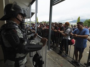 Migrants gather outside the Border Transit Comprehensive Care Center, guarded by security forces, to ask for legal documents that allow them to travel through Mexico, on the outskirts of Huixtla, Chiapas state, Mexico, Friday, June 10, 2022. The group left Tapachula this Monday, tired of waiting to normalize their status in a region with little work, with the ultimate goal of reaching the US.