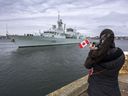 Eine Frau macht ein Foto, als die HMCS Halifax am 19. März Halifax verlässt.