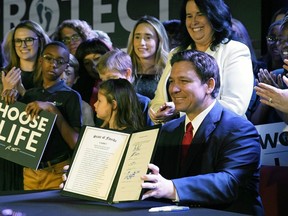 FILE - Florida Gov. Ron DeSantis holds up a 15-week abortion ban law after signing it on April 14, 2022, in Kissimmee, Fla. A synagogue claims in a lawsuit filed Friday, June 10, 2022, that a new Florida law prohibiting abortion after 15 weeks violates religious freedom rights of Jews in addition to the state constitution's privacy protections.