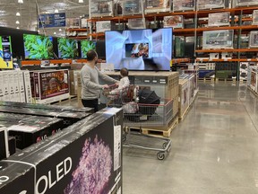 FILE - A shopper pushes a child in a cart while browsing big-screen televisions on display in the electronics section of a Costco warehouse, Tuesday, March 29, 2022, in Lone Tree, Colo. U.S. retail sales rose 0.9% in April, a solid increase that underscores Americans' ability to keep ramping up spending even as inflation persists at nearly a 40-year high. The Commerce Department said Tuesday, May 17, that the increase was driven by greater sales of cars, electronics, and at restaurants. Even adjusting for inflation, which was 0.3% on a monthly basis in April, sales increased.