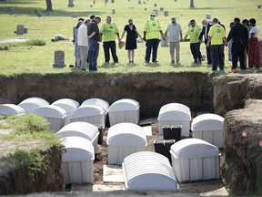 FILE - In this Friday, July 30, 2021, photo, a group prays during a small ceremony as remains from a mass grave are reinterred at Oaklawn Cemetery in Tulsa, Okla. Investigators say another step forward has been taken in efforts to identify possible victims of the Tulsa Race Massacre. The committee overseeing the search for mass graves of victims was told Tuesday, June 21, 2022, that enough usable DNA for testing has been found in two of the 14 sets of remains that were removed from Tulsa's Oaklawn Cemetery a year ago.