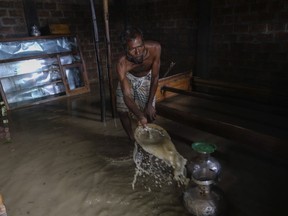 Bangladeshi man tries to remove muddy water from his flooded home in Sylhet, Bangladesh, Wednesday, June 22, 2022.