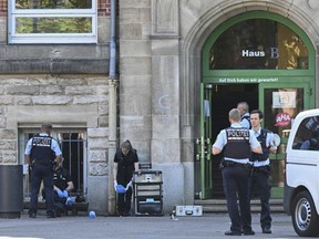 Police officers secure a crime scene in front of a school in Esslingen, Germany, Friday, June 10, 2022. A woman and a child were injured in a violent attack at an elementary school.