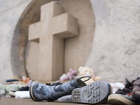 Children's boots sit at the base of a monument that commemorates the original Indian Residential School at George Gordon First Nation on Wednesday April 20, 2022. Saskatchewan is marking National Indigenous Peoples' Day by holding a ceremony for the province's residential school memorial.