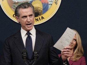 FILE -- California Gov. Gavin Newsom displays a bill he signed that shields abortion providers and volunteers in California from civil judgements from out-of-state courts during a news conference in Sacramento, Calif., June 24, 2022. California lawmakers are expected to vote on the state budget on Wednesday, June 29, 2022, that includes $20 million to help pays for things like travel expenses, lodging and meals for people seeking abortions. But the money can only be used for in-state travel.