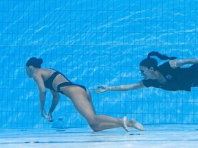 Coach Andrea Fuentes recovers Anita Alvarez, left, from the bottom of the pool after she fainted in the women's solo free artistic swimming finals, during the Budapest 2022 World Aquatics Championships.