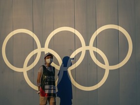 FILE - A volunteer walks past the Olympic rings ahead of the 2020 Summer Olympics, in Tokyo on July 22, 2021. Japan's northern city of Sapporo on Monday, June 6, 2022, rejected holding a referendum to give voters a choice over bidding for the 2030 Winter Olympics. The city's assembly, controlled by Japan's Liberal Democratic Party, which is also in charge of the national government, turned down having a public vote. Its meeting was streamed online.
