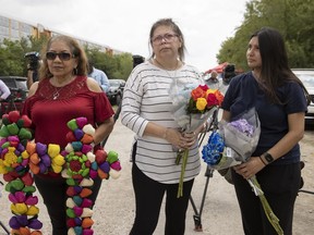 Angelita Olvera, left to right, Marissa Hernandez, and her daughter Delilah Hernandez, pay their respects at the scene on Quintana Road, Tuesday, June 28, 2022, in San Antonio, where officials say dozens of people have been found dead and multiple others were taken to hospitals with heat-related illnesses after a semitrailer containing suspected migrants was found.