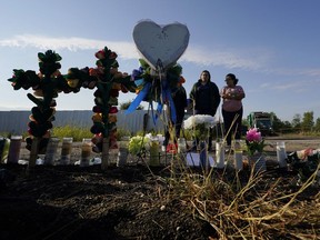 Mourners pay their respects at a makeshift memorial at the site where officials found dozens of people dead in an abandoned semitrailer containing suspected migrants, Wednesday, June 29, 2022, in San Antonio.