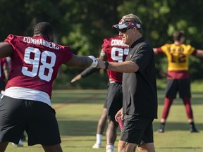 Washington Commanders NFL football team defensive coordinator Jack Del Rio, gives defensive tackle Phidarian Mathis (98) a fist bump during the team's NFL football practice in Ashburn, Va., Wednesday, June 1, 2022.