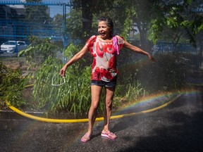Pinky, who asked to be identified only by her first name, reacts as she cools off in the water at a temporary misting station in the Downtown Eastside of Vancouver, B.C., on Monday, June 28, 2021.Environment Canada says heat warnings will persist in British Columbia and Yukon for at least another day, but cooler conditions are on the way.