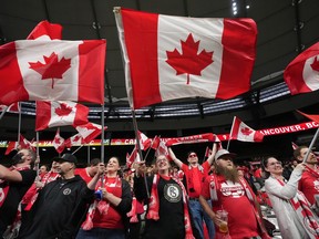 Fans wave Canadian flags before Canada and Curacao play a CONCACAF Nations League soccer match, in Vancouver, B.C., Thursday, June 9, 2022.