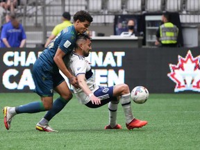 York United's Osaze De Rosario, left, and Vancouver Whitecaps' Erik Godoy vie for the ball during the first half of a Canadian Championship semifinal soccer match, in Vancouver, on Wednesday, June 22, 2022.