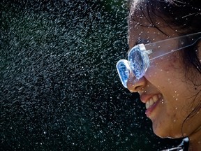 Leanne Opuyes uses a spray bottle to mist her face while cooling off in the frigid Lynn Creek water in North Vancouver, B.C., on Monday, June 28, 2021.&ampnbsp;The first hot weather stretch of the summer in British Columbia has resulted in Environment Canada issuing heat warnings for large sections of the province.&ampnbsp;THE CANADIAN PRESS/Darryl Dyck