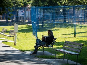 A man plays a guitar in the shade at Oppenheimer Park in the Downtown Eastside of Vancouver, British Columbia, on June 28, 2021, during the heat dome event that set temperature records across the province.