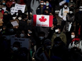 A person holds a Canadian flag sign with the words "No Hate" on it during a rally opposing discrimination against Asian communities and to mourn the victims of those affected by the Atlanta shootings, in Vancouver, on Sunday, March 28, 2021.