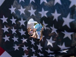 Abortion rights activists are seen through a hole in an American flag as they protest outside the Supreme Court in Washington, Saturday, June 25, 2022. The Supreme Court's decision to overturn national protections for abortion has set off a contest between Democratic and Republican lawmakers over whose policies would do more to help vulnerable mothers and children. It's a key issue going into the midterm elections.