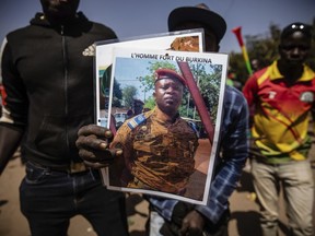 FILE - A man holds a portrait of Lt. Col. Paul Henri Sandaogo Damiba who has taken the reins of Burkina Faso, in Ouagadougou, Jan. 25, 2022. Attacks by Islamic extremists are on the rise five months after mutinous soldiers overthrew Burkina Faso's democratically elected president in January. And analysts say that could undermine support for Damiba's regime. Writing on portrait reads in French "The strong man of Burkina".
