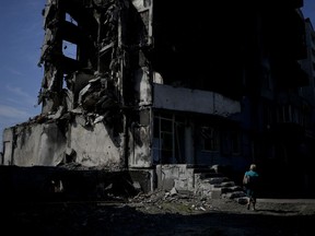A woman walks past a building destroyed in Russian shelling in Borodyanka, on the outskirts of Kyiv, Ukraine, Tuesday, June 21, 2022.