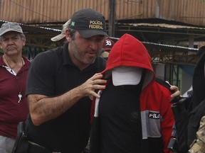 A federal police officer escorts a suspect towards a river in the area where Indigenous expert Bruno Pereira and freelance British journalist Dom Phillips disappeared, in Atalaia do Norte, Amazonas state, Brazil, Wednesday, June 15, 2022. Federal police said in a statement Tuesday night that they had arrested a second suspect in connection with the disappearance of Phillips and Pereira in a remote area of the Amazon.