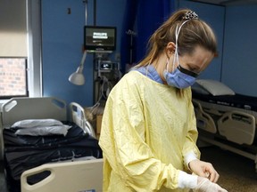 Registered nurse Courtney Benoit dons gloves and other personal protective equipment before tending to a patient Thursday, Feb. 10, 2022 in the special-care unit of Campbellford Memorial Hospital in Campbellford, Ont.