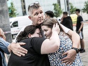 People hug each other in front of the Fields shopping mall, where a gunman killed three people and wounded several others in Copenhagen on July 3, 2022.
