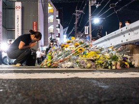 Eine Frau reagiert vor einem provisorischen Denkmal, wo Menschen Blumen an der Szene vor dem Bahnhof Yamato-Saidaiji in Nara niederlegen, wo der frühere japanische Premierminister Shinzo Abe früher am Tag am 8. Juli 2022 erschossen wurde.